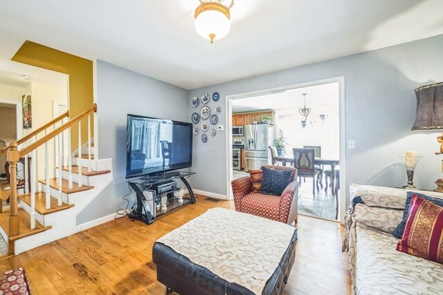 living room with baseboards, visible vents, stairway, and light wood-type flooring