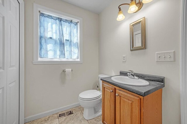 half bath with visible vents, tile patterned flooring, vanity, toilet, and baseboards