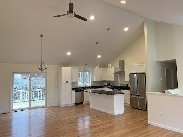 kitchen featuring wall chimney range hood, appliances with stainless steel finishes, white cabinetry, hanging light fixtures, and a center island