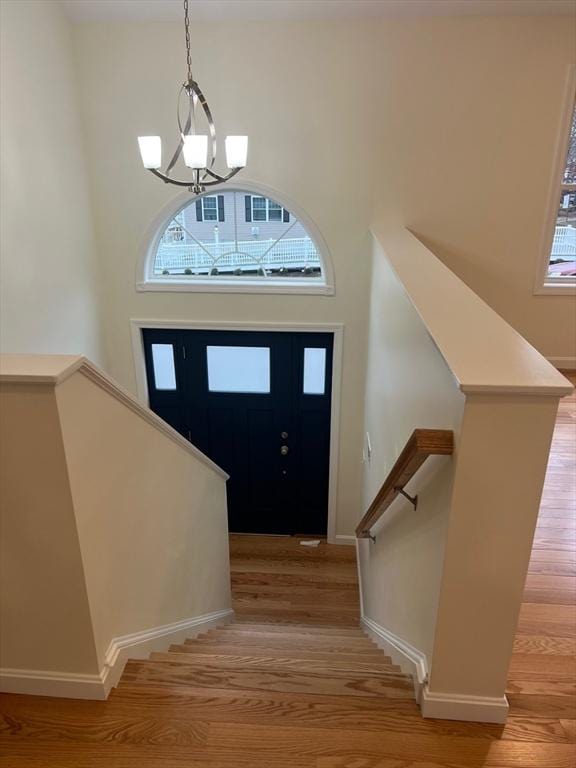 entrance foyer with an inviting chandelier, plenty of natural light, and light wood-type flooring