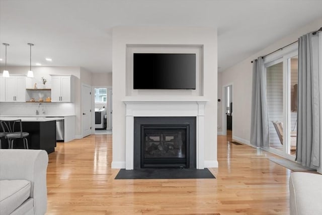 27 Sophia Dr, Rehoboth, MA 02769 - living area featuring light wood-style floors, recessed lighting, a fireplace with flush hearth, baseboards, and washer / clothes dryer