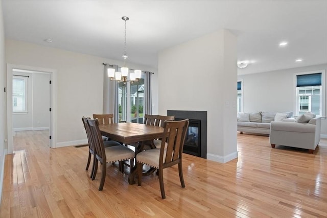 27 Sophia Dr, Rehoboth, MA 02769 - dining area featuring a chandelier, light wood-type flooring, baseboards, and a multi sided fireplace