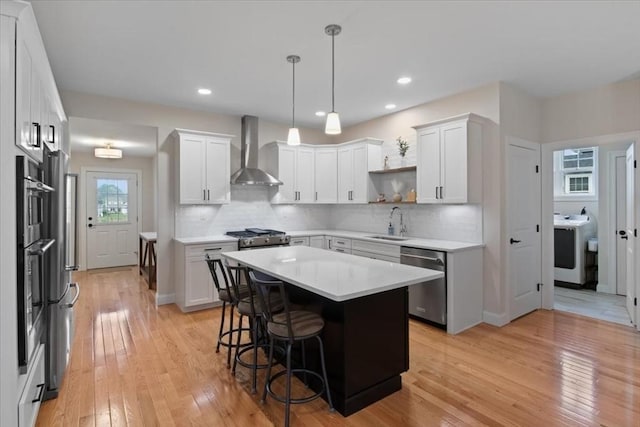 27 Sophia Dr, Rehoboth, MA 02769 - kitchen with wall chimney exhaust hood, appliances with stainless steel finishes, light countertops, a sink, and light wood-type flooring