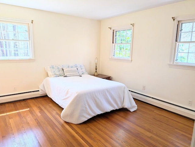 bedroom featuring wood finished floors and a baseboard radiator