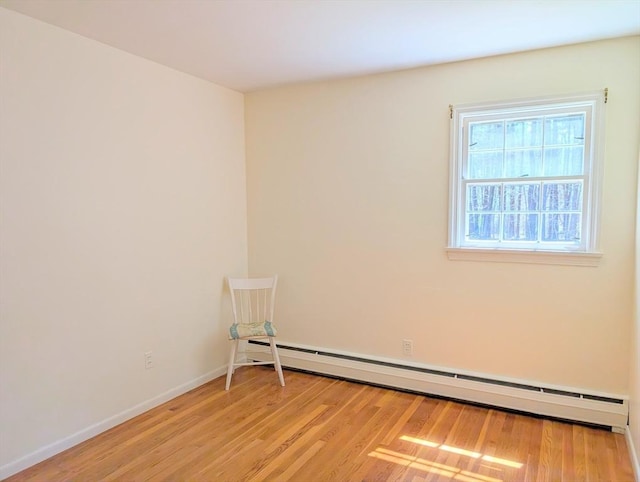 empty room with a baseboard radiator, baseboards, and light wood-type flooring