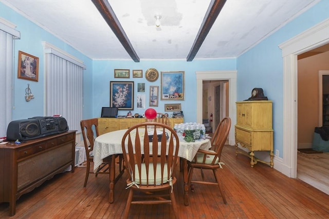 dining room featuring hardwood / wood-style floors and beamed ceiling