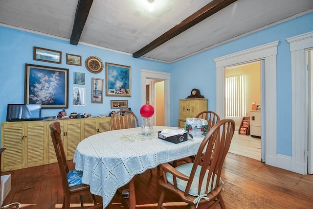 dining room featuring hardwood / wood-style floors and beam ceiling