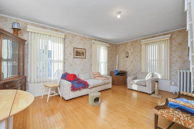 living room with wood-type flooring, plenty of natural light, ornamental molding, and radiator heating unit