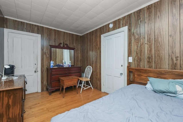 bedroom with hardwood / wood-style flooring, ornamental molding, and wooden walls