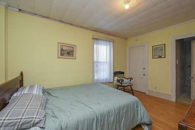 bedroom featuring ornamental molding and light hardwood / wood-style flooring