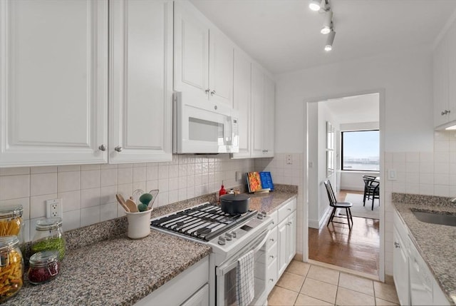 65 E India Unit 27F, Boston, MA 02110 - kitchen with white appliances, light tile patterned floors, white cabinets, and decorative backsplash