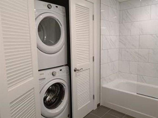 262 Monsignor Obrien Hwy Unit 503, Cambridge, MA 02141 - laundry area featuring stacked washing machine and dryer and dark tile patterned flooring