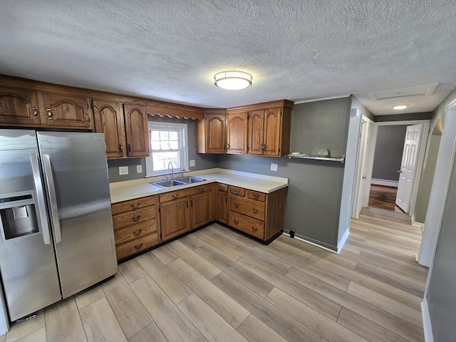 kitchen with sink, light hardwood / wood-style floors, stainless steel fridge with ice dispenser, and a baseboard heating unit