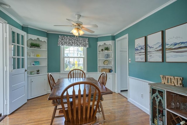 242 Furnace Brook Pkwy, Quincy, MA 02169 - dining room featuring a wainscoted wall, light wood-style flooring, ceiling fan, and crown molding
