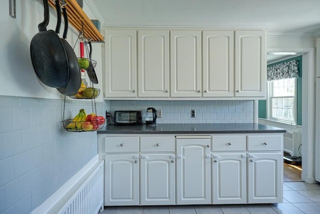 242 Furnace Brook Pkwy, Quincy, MA 02169 - kitchen with radiator, white cabinets, crown molding, light tile patterned floors, and backsplash