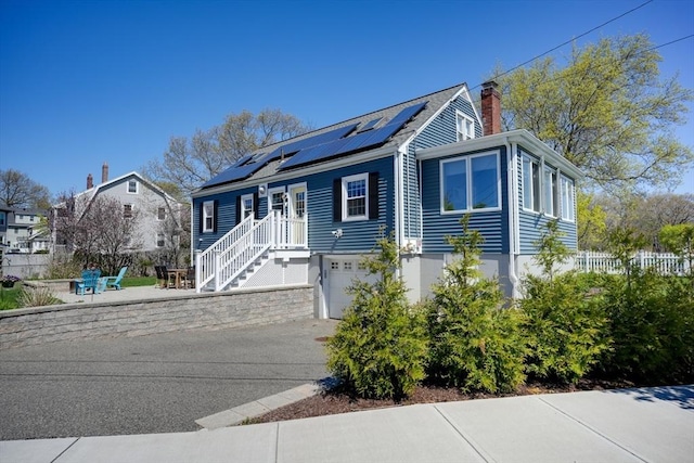 242 Furnace Brook Pkwy, Quincy, MA 02169 - view of front of home featuring solar panels, an attached garage, and a chimney