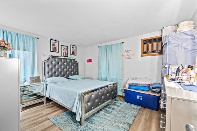 bedroom with a wall unit AC and light hardwood / wood-style flooring