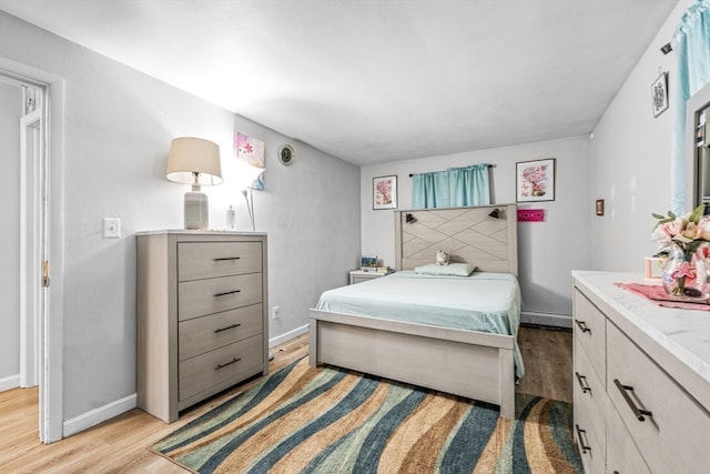 bedroom featuring light wood-type flooring and a baseboard heating unit