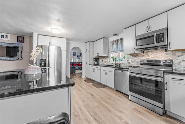 kitchen featuring backsplash, stainless steel appliances, sink, light hardwood / wood-style flooring, and white cabinetry