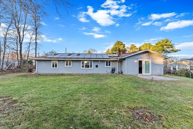 rear view of house featuring a yard, a patio, and solar panels