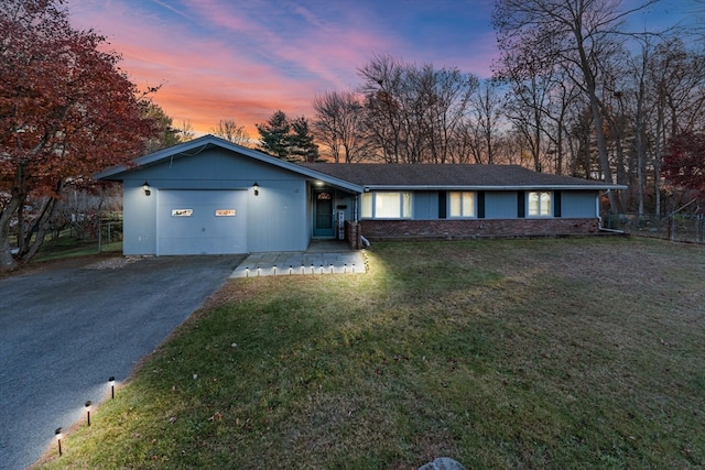 ranch-style house with a garage and a lawn