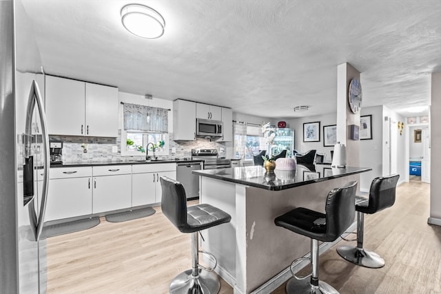 kitchen with white cabinetry, appliances with stainless steel finishes, and light hardwood / wood-style flooring