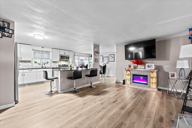 living room with a premium fireplace, sink, and light wood-type flooring