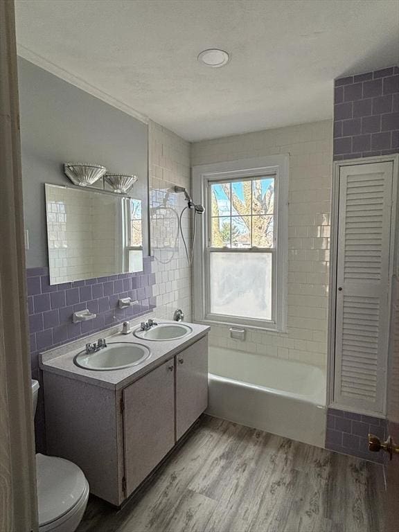 full bathroom with hardwood / wood-style floors, vanity, crown molding, toilet, and tile walls