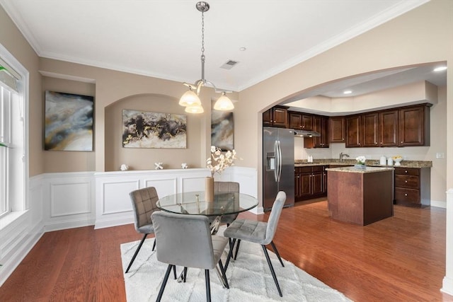 dining room with hardwood / wood-style flooring, an inviting chandelier, crown molding, and sink