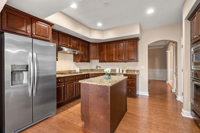 kitchen with light stone counters, a center island, light hardwood / wood-style flooring, and appliances with stainless steel finishes