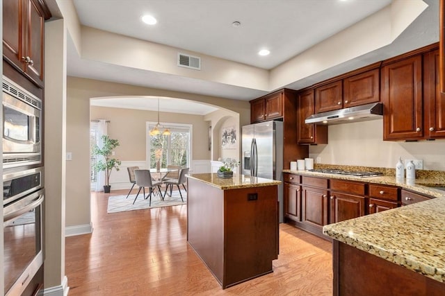 kitchen with stainless steel appliances, pendant lighting, an inviting chandelier, a center island, and light hardwood / wood-style floors