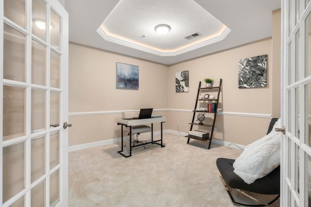 carpeted office space with french doors and a raised ceiling