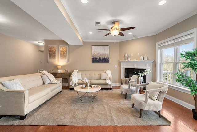 living room featuring wood-type flooring, ceiling fan, and ornamental molding