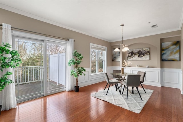 dining area with hardwood / wood-style flooring, an inviting chandelier, and crown molding