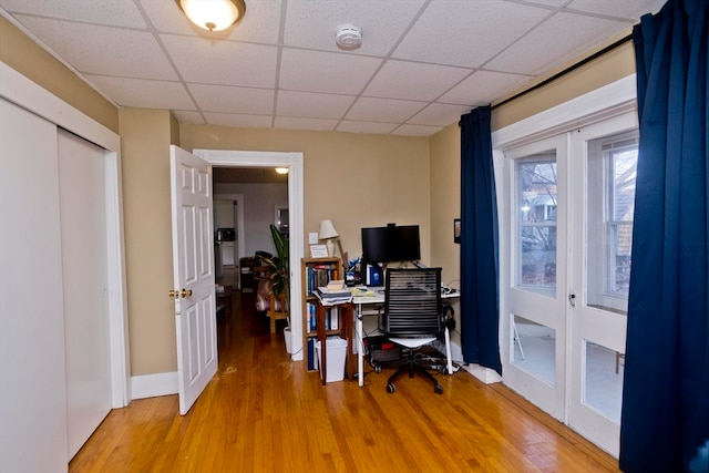 home office featuring wood-type flooring, a paneled ceiling, and french doors