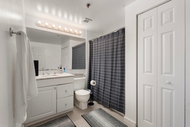 bathroom with walk in shower, vanity, toilet, and tile patterned flooring