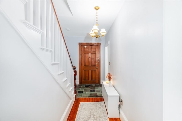 doorway with baseboards, stairway, a chandelier, and wood finished floors