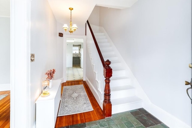 foyer with stairs, baseboards, and a notable chandelier