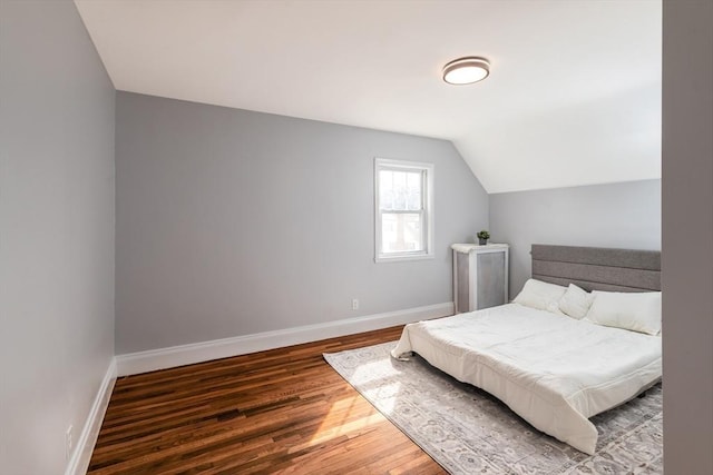 bedroom with lofted ceiling, baseboards, and wood finished floors