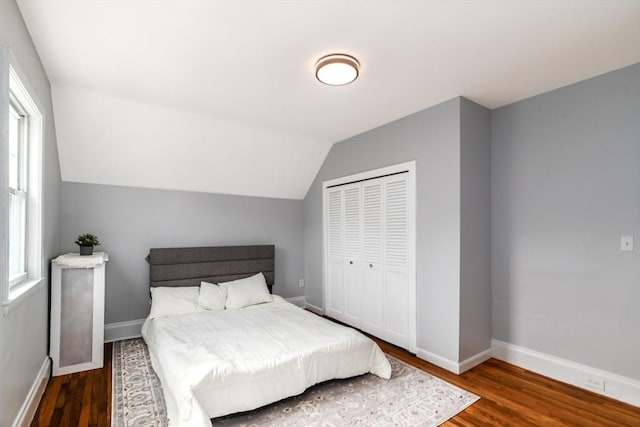 bedroom with a closet, baseboards, vaulted ceiling, and wood finished floors