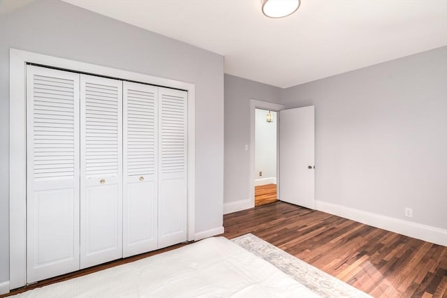 unfurnished bedroom featuring a closet, wood finished floors, and baseboards