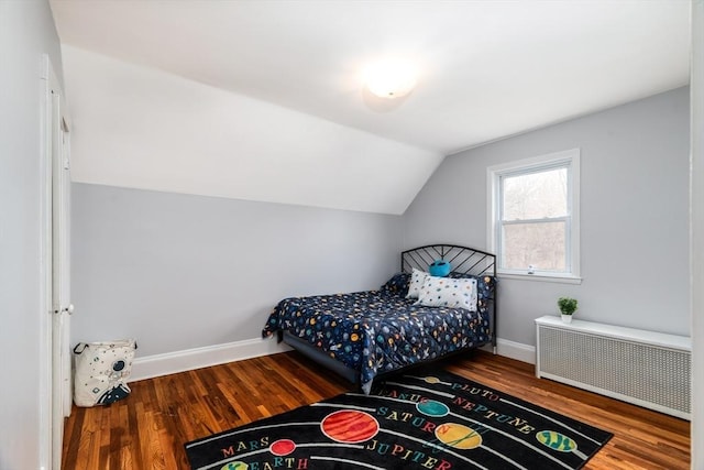 bedroom with vaulted ceiling, radiator heating unit, wood finished floors, and baseboards