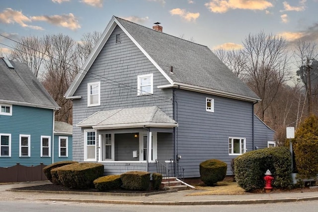 view of front of home featuring a chimney and roof with shingles