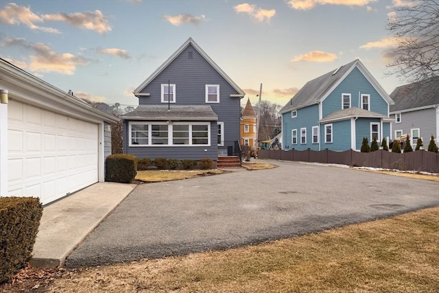 view of front of house featuring driveway, a garage, and fence