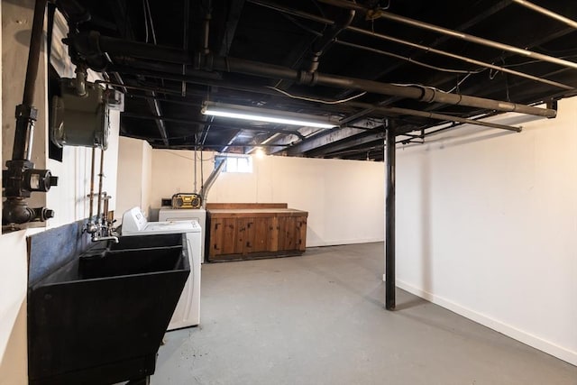 below grade area featuring baseboards, a sink, and washing machine and clothes dryer