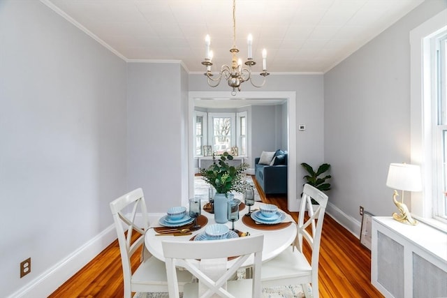 dining room with wood finished floors, baseboards, radiator heating unit, an inviting chandelier, and crown molding