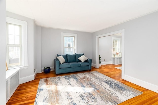 living room featuring crown molding, light wood-style flooring, and baseboards