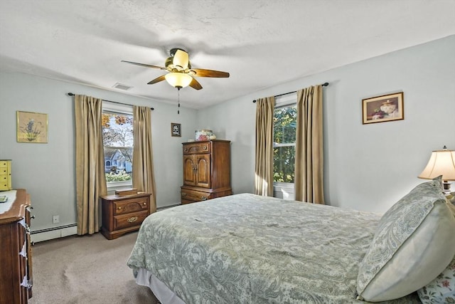 carpeted bedroom featuring a baseboard heating unit, multiple windows, and ceiling fan