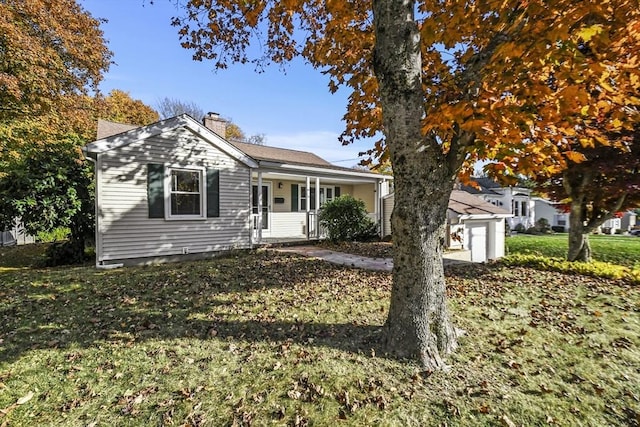 view of front of property featuring a chimney, a porch, and a front yard