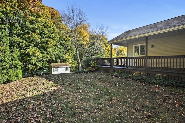 view of yard featuring an outdoor structure, a wooden deck, and a storage unit